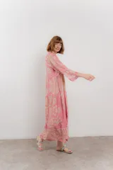 Vestido largo azul con estampado floral en tonos beige, confeccionado en viscosa. Presenta escote en V, botonadura completa en el frente y mangas largas con volados.