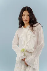 Camisa blanca de algodón con volados delicados en el frente y mangas largas abullonadas.
