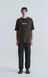 Remera negra con efecto gastado, de corte oversize y manga corta. Estampado en la espalda con dibujos de estilo esotérico en tonos violeta y naranja, y la palabra 'MAGIA' en blanco.
