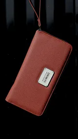 Billetera larga negra con cierre perimetral y placa metálica con logo. Posee múltiples compartimentos internos para tarjetas y documentos, además de un bolsillo con cierre interior. Incluye correa de mano desmontable.
