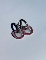 Par de aros colgantes con argollas doradas y dijes circulares de resina transparente con incrustaciones de strass de colores. El dije mide aproximadamente 1.5cm de diámetro.