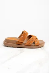 Sandalias marrones de gamuza con apliques de tachas doradas, con dos tiras anchas sobre el empeine y suela plana.