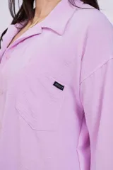 Camisa negra de corte amplio, con cuello clásico, cierre frontal con botones, manga larga con puños arremangados y bolsillo de parche en el pecho.