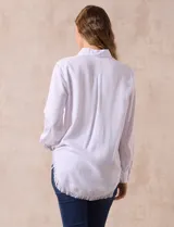 Camisa blanca de lyocell, marca Hester & Orchard. Tiene cuello con solapa, abertura central con botones, bolsillo aplicado en el pecho y ruedo desflecado.