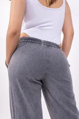 Pantalón deportivo gris con efecto lavado, corte ancho, cintura elástica y logo bordado en negro.