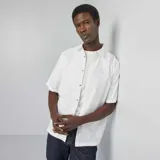 Camisa blanca de manga corta con cuello clásico y cierre abotonado.