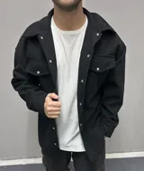 Chaqueta negra de paño con cuello clásico, cierre frontal con botones a presión, dos bolsillos de parche en el pecho y corte holgado.