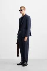 Pantalón de vestir azul marino, de corte slim fit, con bolsillos laterales y traseros de doble vivo con botón. Se ajusta a la cintura con cierre frontal con cremallera y botón.