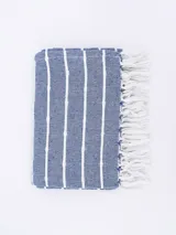 Pie de cama rectangular de tejido plano color azul con rayas verticales blancas y flecos blancos en los extremos.