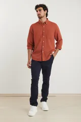 Camisa azul marino de lino y algodón, con cuello abotonado, manga larga con puños enrollados, bolsillo de parche en el pecho y cierre frontal con botones.