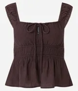 Blusa blanca con breteles anchos y escote cuadrado, detalle de lazo ajustable en el centro del busto y volado en el ruedo. El tejido es texturizado y ligero.