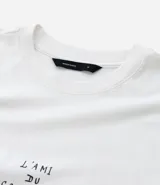 Remera boxy de algodón color crudo, con cuello redondo y mangas cortas. Estampa frontal con la frase "l'ami du contraire" y estampa trasera de figuras estilo art noveau.