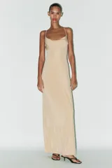 Vestido largo color beige de tejido de punto, con escote drapeado y tirantes finos ajustables. Espalda descubierta con escote drapeado y tira con gancho metálico.