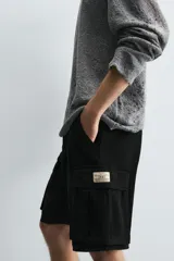 Bermuda cargo de algodón color marrón oscuro, tiro medio, corte regular, con bolsillos laterales de parche con solapa y bolsillos traseros de vivo.