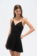 Vestido corto negro de breteles finos, con escote en V, frunces en el busto y falda acampanada.