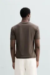 Camiseta marrón de corte slim fit, confeccionada en tejido de algodón con elasticidad, cuello redondo y manga corta.