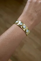 Pulsera rígida de bronce color dorado con cinco incrustaciones de nácar.