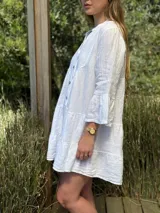 Vestido corto negro de lino, con escote en V, botones frontales y mangas largas acampanadas con volados.