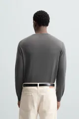 Jersey negro de lana con acabado mercerizado, corte relaxed fit, cuello redondo y mangas largas con terminaciones en rib.