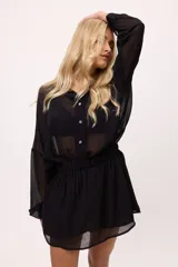 Vestido corto color verde lima, estilo camisero, confeccionado en chiffon transparente. Tiene cuello camisero, mangas largas abullonadas y elástico en la cintura.