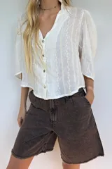 Blusa blanca de algodón liviano con bordado vertical, manga 3/4, cuello mao y cierre frontal con botones.