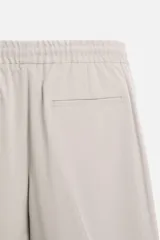 Pantalón color arena de corte recto, confeccionado en tejido elástico. Cuenta con cintura elástica ajustable con cordón, bolsillos laterales y bolsillos de vivo en la parte trasera.