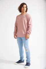 Jean skinny de hombre color negro, ajustado desde la cadera hasta los tobillos, con roturas en las rodillas y logo bordado en el bolsillo trasero.