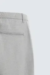 Pantalón largo de vestir gris claro con estampado de cuadros, corte slim fit y cintura elástica. Confeccionado en tejido con alta elasticidad, bolsillos frontales y cierre frontal con cremallera y botón.