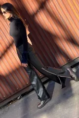 Pantalón Oxford de cuero negro con cierre frontal y pasamanería plateada en los tajos laterales.