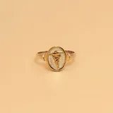 Anillo plateado con apliques dorados, con forma ovalada y símbolo de medicina en el centro.