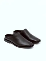 Mocasín negro de cuero con punta cuadrada y talón descubierto.