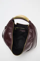 Bolso de mano ovalado color marrón oscuro, con asa de hombro metálica dorada y cierre superior con cremallera.