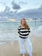 Pantalón de algodón con motivo rayado en tonos claros (blanco y celeste/azul muy claro), de calce recto y cintura elastizada. Presenta bolsillos delanteros y un detalle bordado en la pierna.