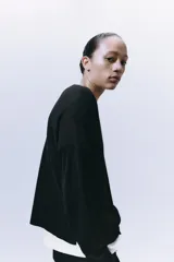 Jersey de punto liso, color azul brillante, con cuello redondo y manga larga. Presenta acabados en rib en puños, cuello y bajo, con aberturas laterales en el ruedo.