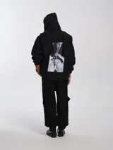 Buzo hoodie oversize de felpa de algodón color gris, con capucha y bufanda integrada que envuelve el cuello. Presenta cierre frontal y bolsillos canguro.