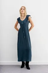 Vestido largo negro de poliéster con escote redondo, espalda baja y volados en escote delantero y trasero. Tiene cordón de ajuste en la cintura con terminaciones metálicas.