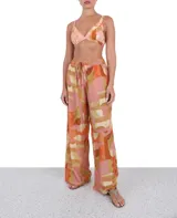 Pantalón palazzo con estampado geométrico en tonos rosados, naranjas y beige, con cintura elástica y cordón ajustable.