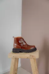 Botas cortas de cuero color hueso, con puntera redondeada, ajuste con doble tira con velcro color verde oliva y suela track color negro.