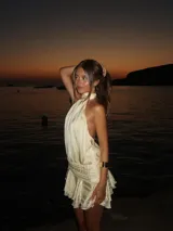 Minivestido color crema con cuello halter, espalda descubierta y falda con volados.