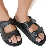 Sandalias planas negras de cuero con textura y múltiples correas ajustables con velcro.