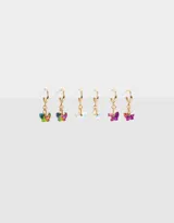 Set de tres pares de aros tipo argolla dorados con dijes de mariposas colgantes en diferentes colores: multicolor, blanco iridiscente, violeta y fucsia.
