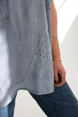 Blusa celeste de corte holgado con mangas cortas y detalle de bordado calado en el frente.
