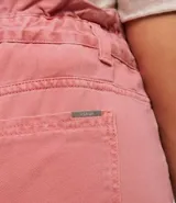 Pantalón clochard de jeans color rosa viejo, con cintura fruncida, cierre por botón y cremallera, pequeño bolsillo delantero y bolsillos delanteros y traseros.