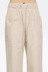 Pantalón corte jogger color beige, con largo tobillero, bolsillos tipo alforja y logo bordado. Cintura elástica ajustable con cordones.