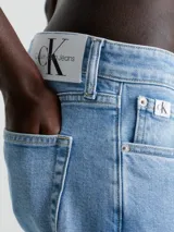 Jeans celeste de corte slim fit, tiro medio y pierna cónica. Diseño clásico de cinco bolsillos, con cierre de botón y cremallera.