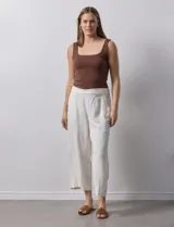 Pantalón de lino color crudo, de corte ancho y tiro alto, con bolsillos laterales y cintura elástica.