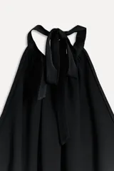 Top negro con cuello halter ajustable con lazadas, espalda descubierta y bajo redondeado.