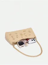 Cartera de mano color beige, tejida en rafia, con cadena dorada y apliques de dijes con forma de estrellas de mar, caracoles y perlas.