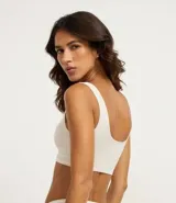 Top tipo bralette sin aros ni copas, color beige claro, con escote cuadrado y tirantes medianos. Presenta una banda inferior texturizada con doble línea horizontal.
