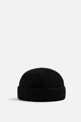 Gorro negro corto de punto con ajuste con trabilla y acabado con vuelta.